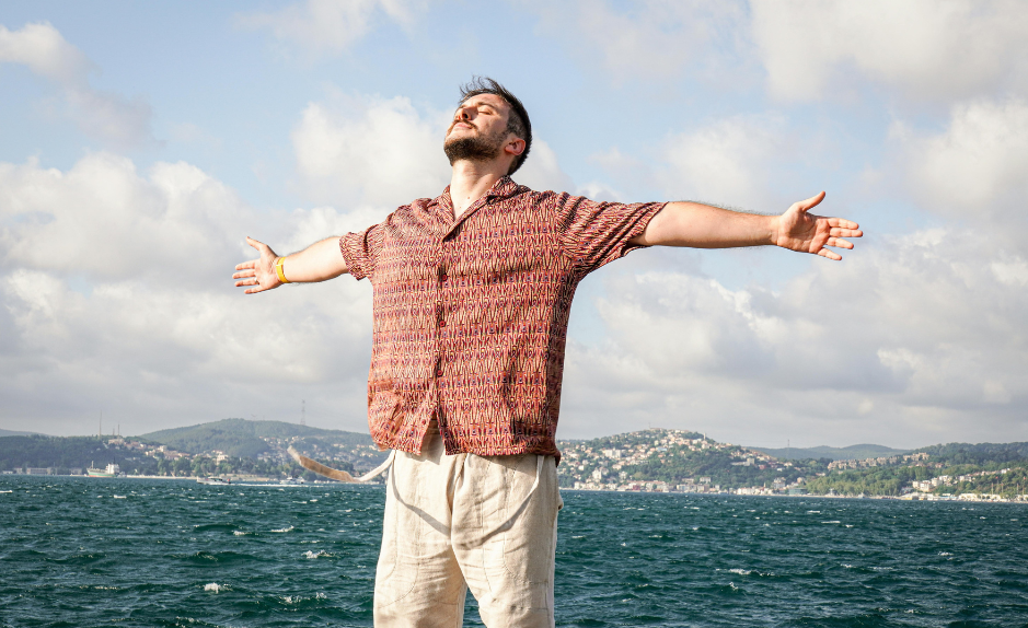 Personne debout en plein air, les bras ouverts, illustrant le bien-être, la respiration et la régulation émotionnelle