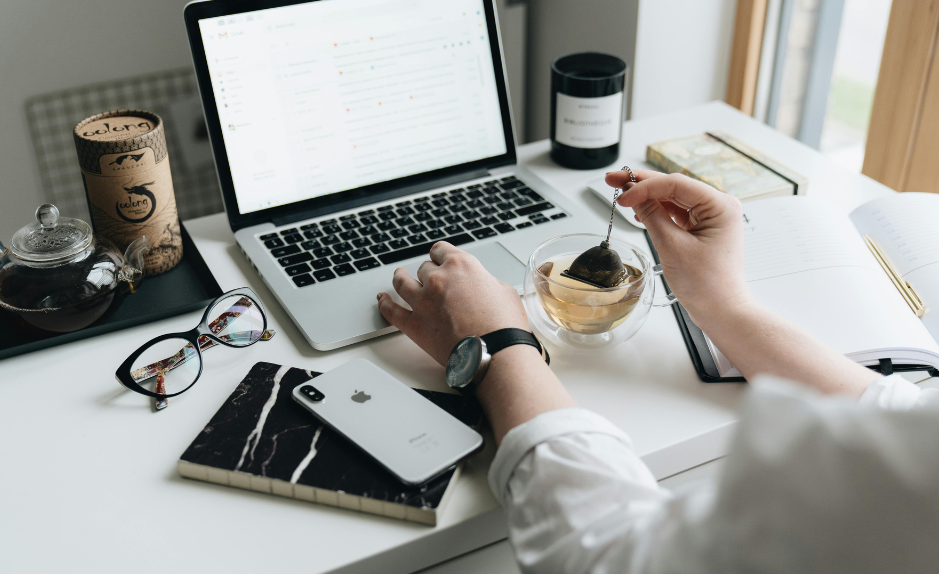 Personne travaillant sur un ordinateur portable en buvant une tisane, illustrant un moment de calme et de réflexion