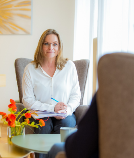 Delphine Malapert dans un fauteuil prenant des notes face à une personne, dans un cabinet lumineux.